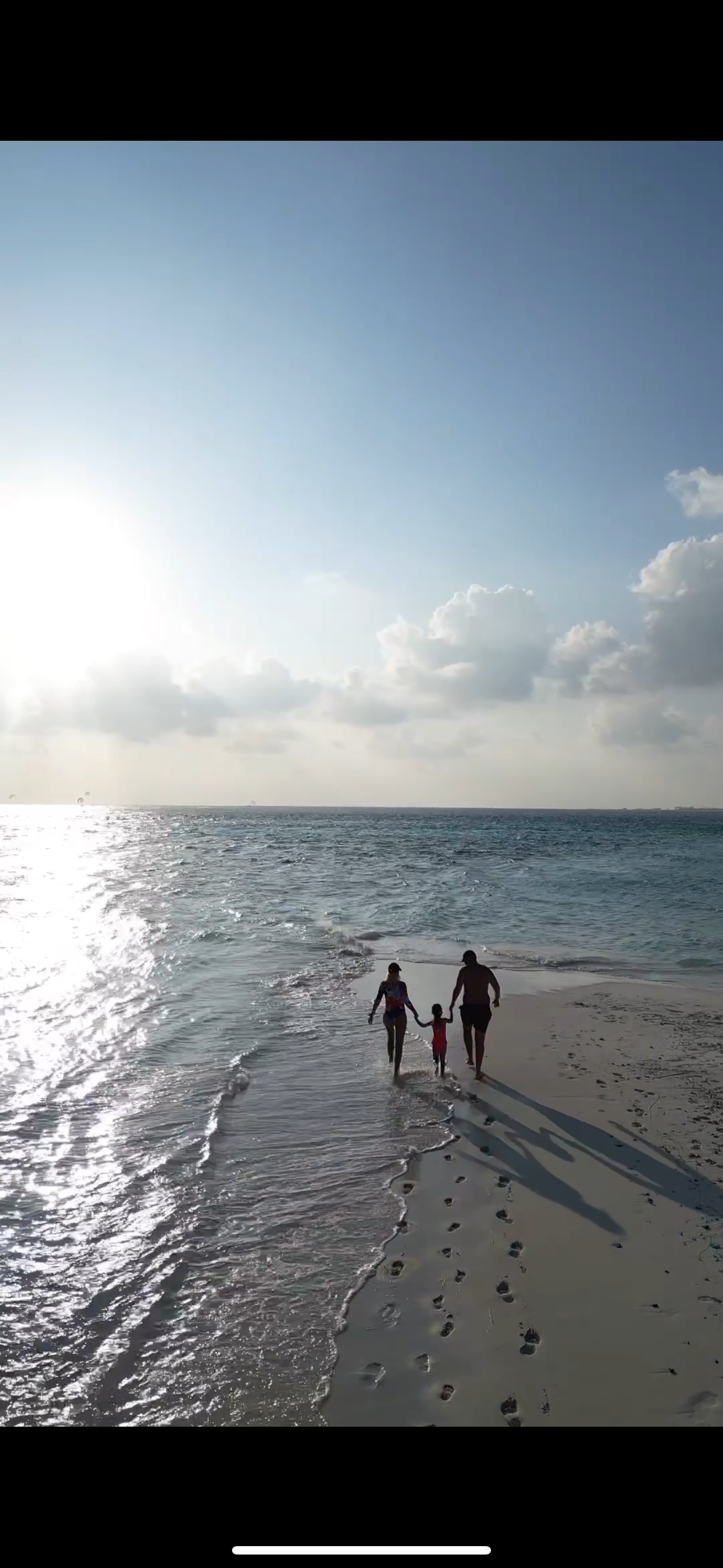 Familia caminando por la playa al atardecer en Maldivas